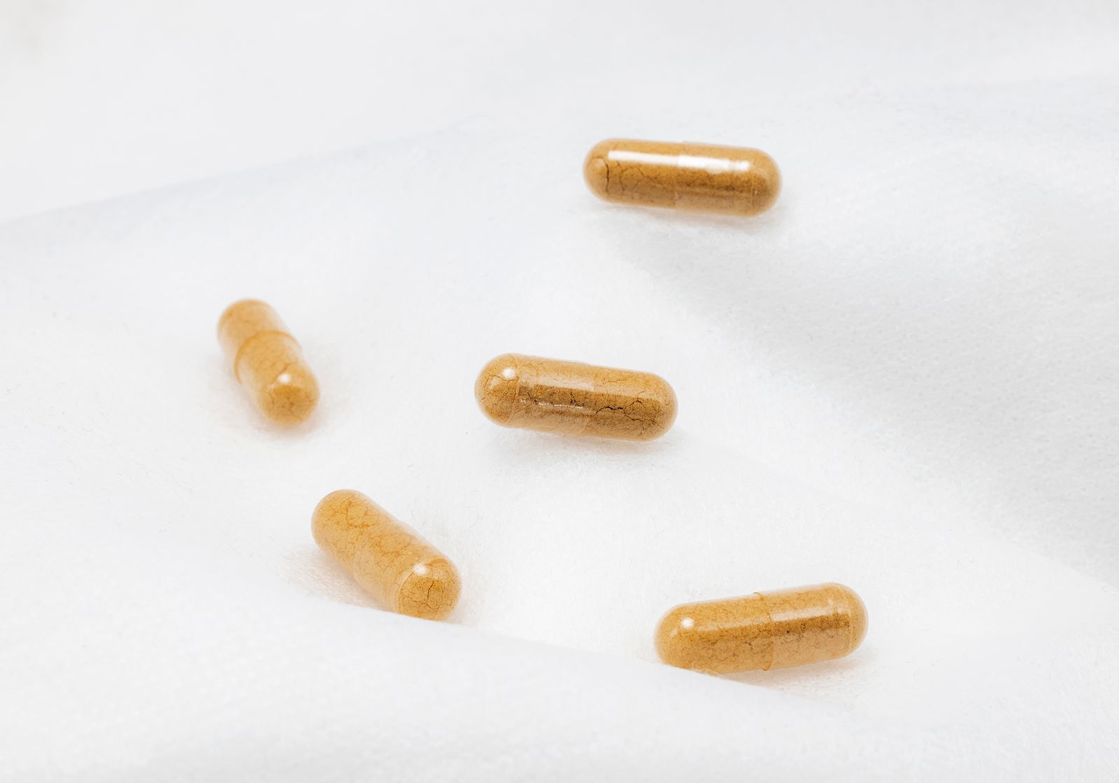 Minimal top-down arrangement of supplement capsules on a clean white surface.